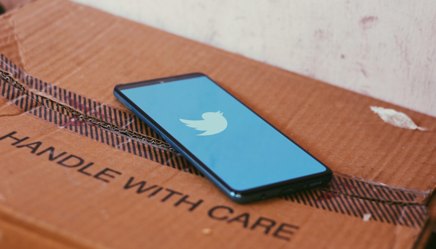 Twitter app on an iPhone that is resting on a cardboard box that reads handle with care
