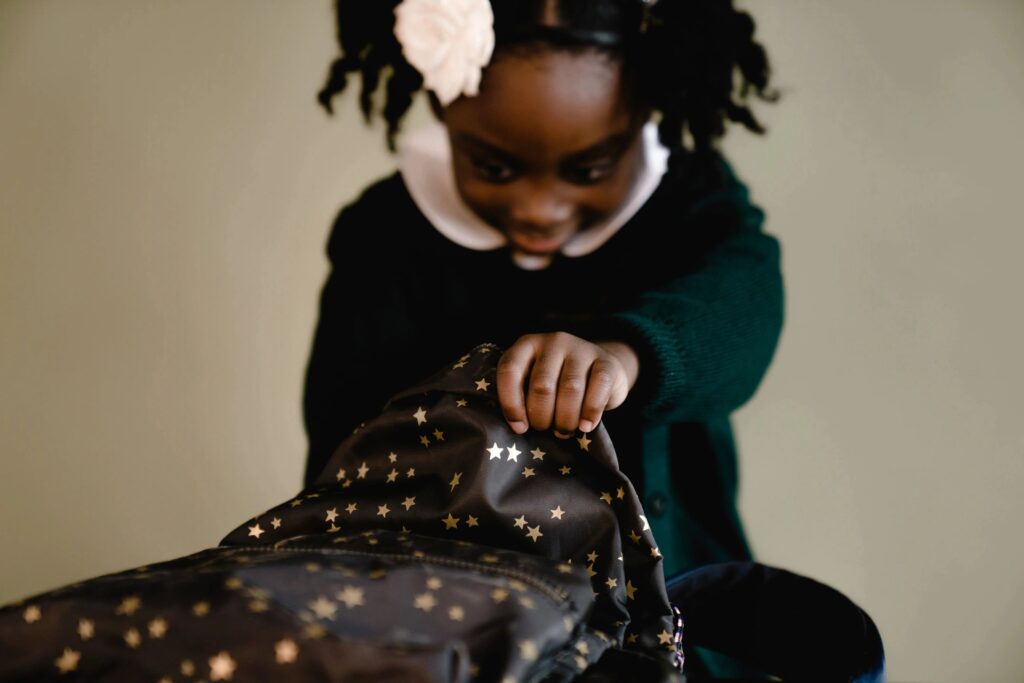 Little girl opening a black backpack with stars on it