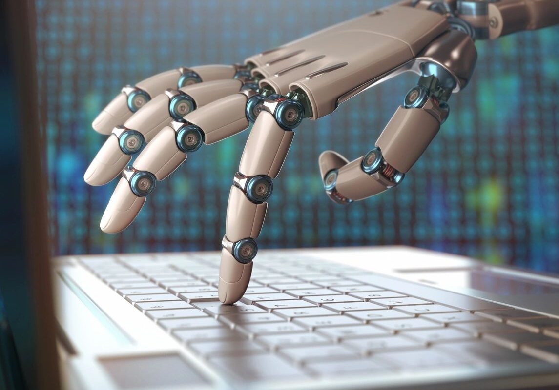 Close-up of robot hand typing on laptop computer