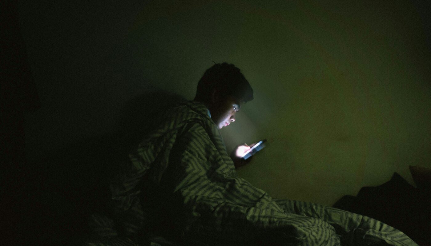 Person scrolling in bed in the dark