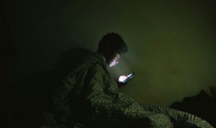 Person scrolling in bed in the dark