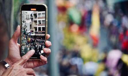 Person holding up a phone to record a street filled with people.