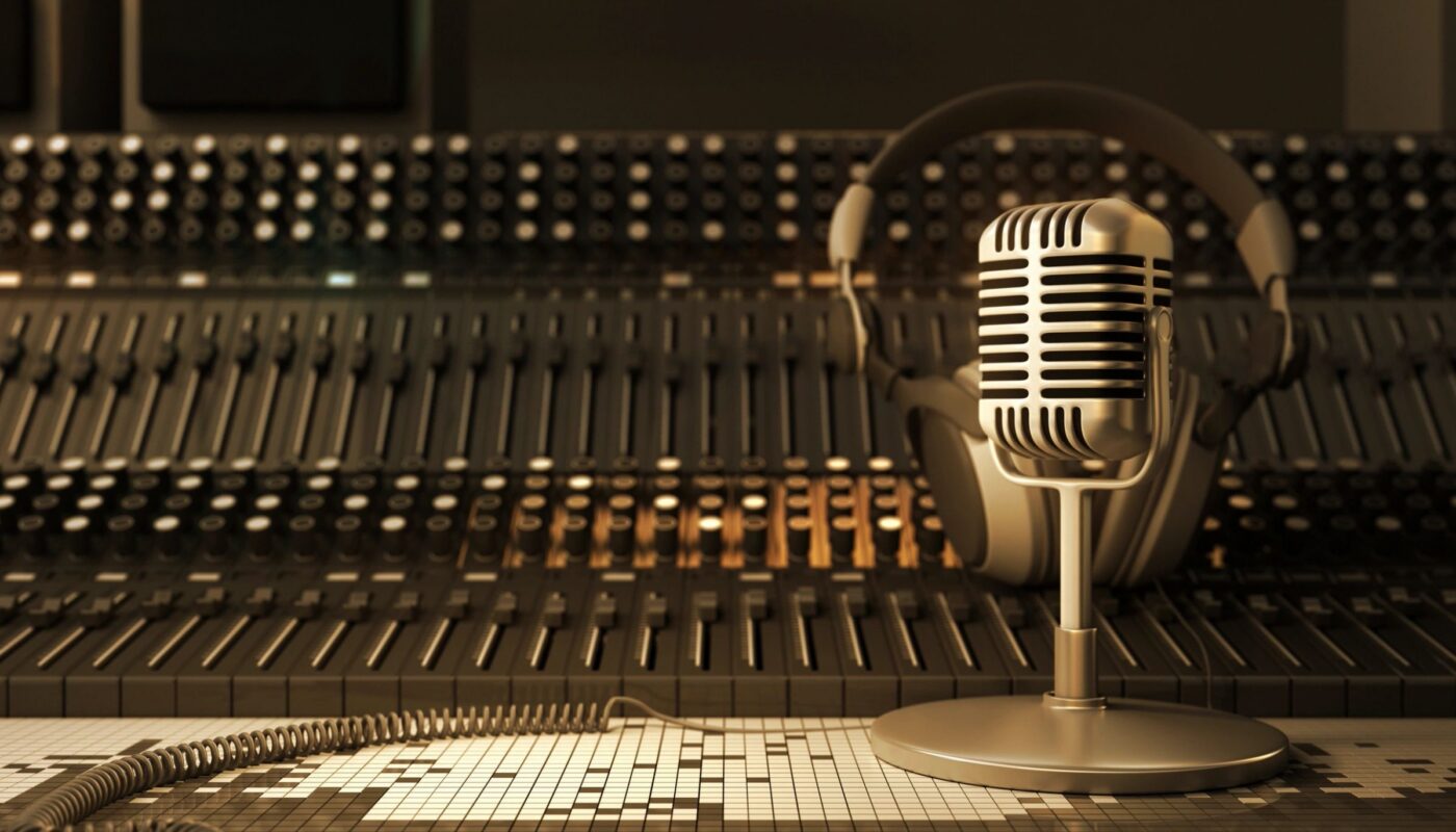 A recording studio: a mixing board, with a mic with headphones sitting on top of it.